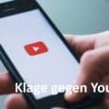 Hand hält Smartphone, YouTube wird auf Bildschirm angezeigt